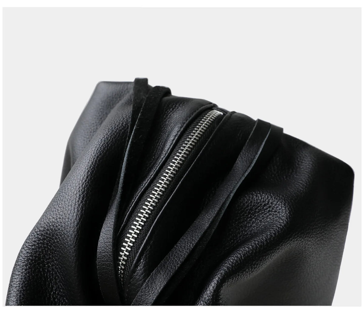 Black leather bag with a zipper on a light gray background