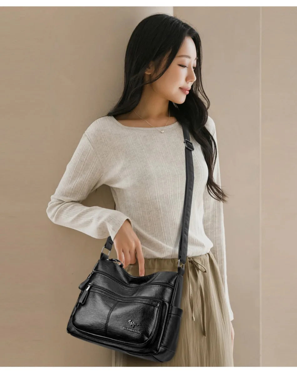 Woman holding a black handbag against a beige background