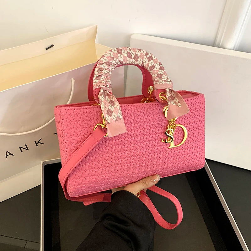 Pink handbag with decorative handle held by a person, with a Dior logo visible.