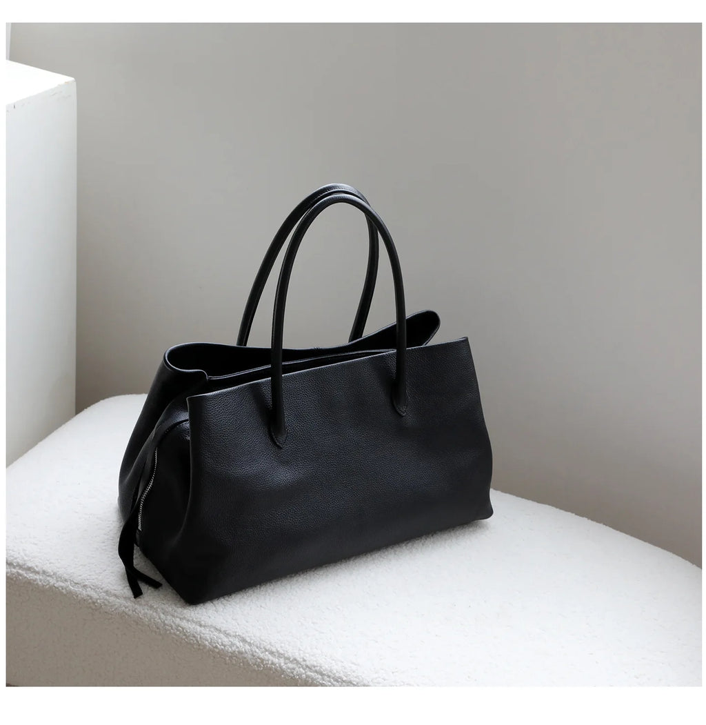 Black handbag on a white surface with a neutral background