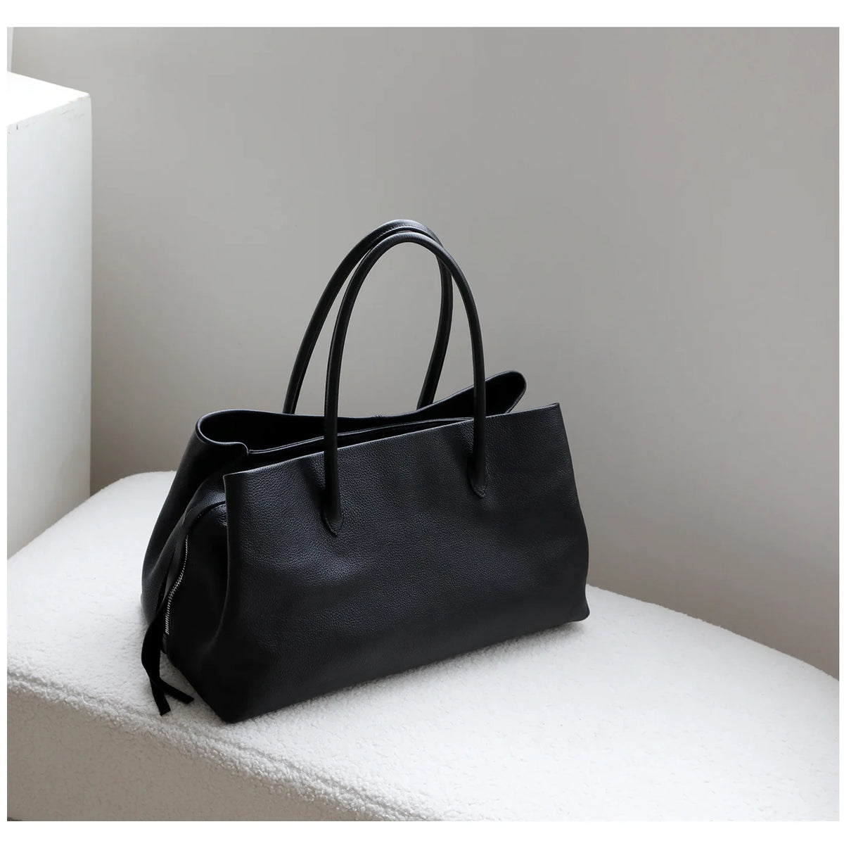 Black handbag on a white surface with a neutral background