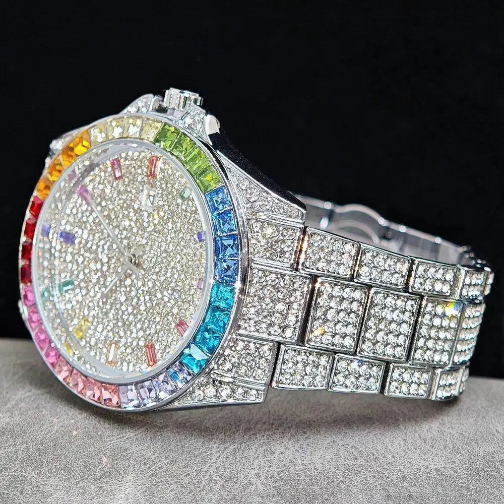 A close-up of a silver-toned wristwatch covered in clear rhinestones, featuring a colorful rainbow crystal bezel and a matching rhinestone bracelet, set against a black background.