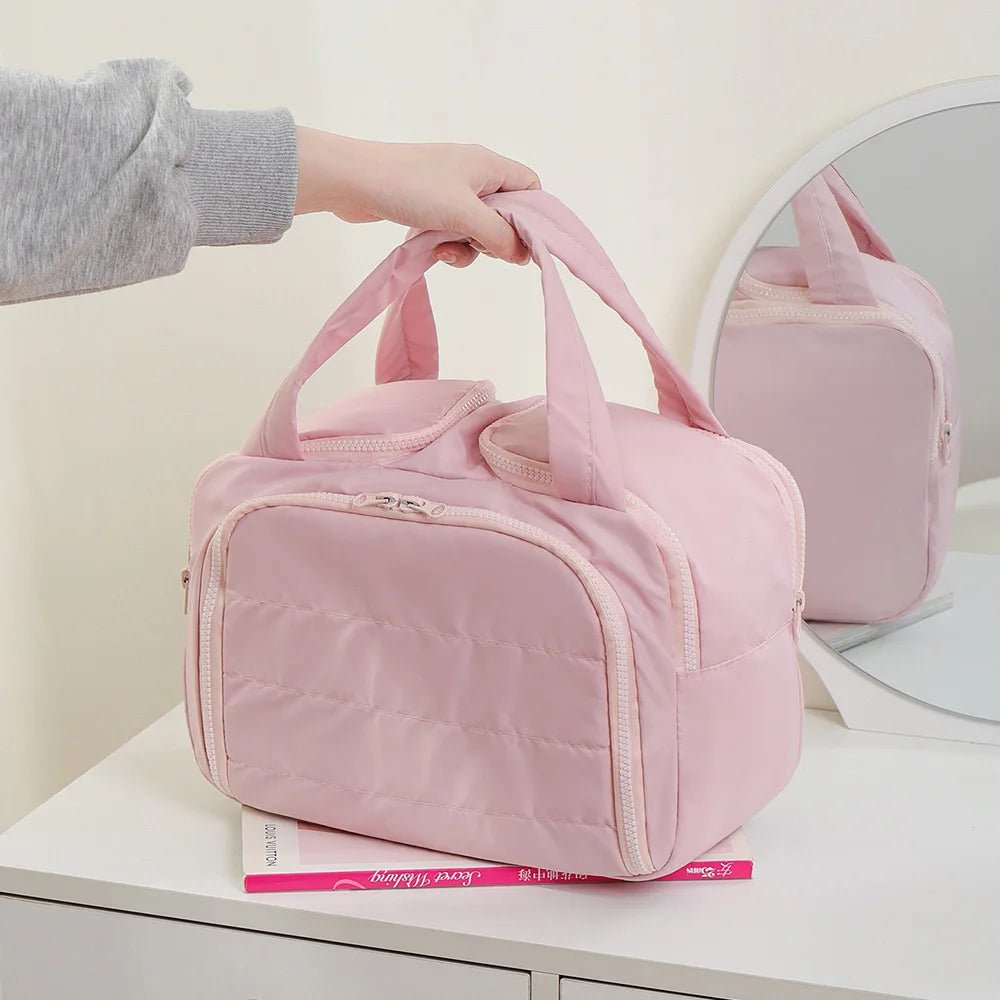 Pink travel bag being held by a person on a white surface with a mirror reflection.