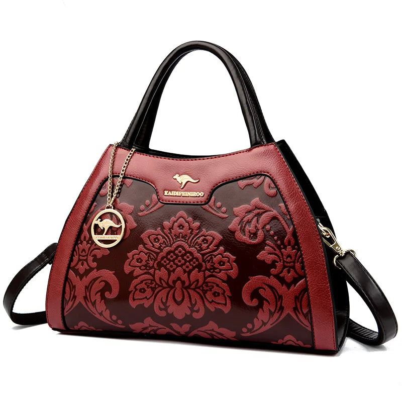 Red floral-patterned handbag with black accents on a white background