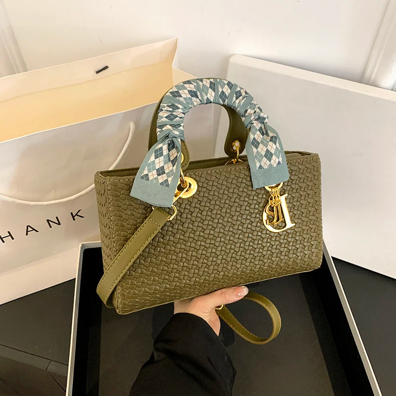 Green handbag with patterned handle held by a person, with a 'Dior' logo visible.
