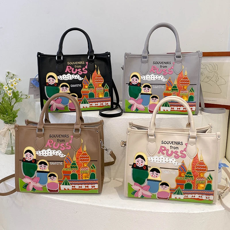 Four tote bags with colorful cartoon matryoshka and Kremlin illustrations, displayed on a white riser against a light background.