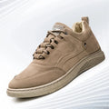 A single low-top casual sneaker in taupe brown suede, shown from a three-quarters angle on a light gray background with subtle diagonal lines.