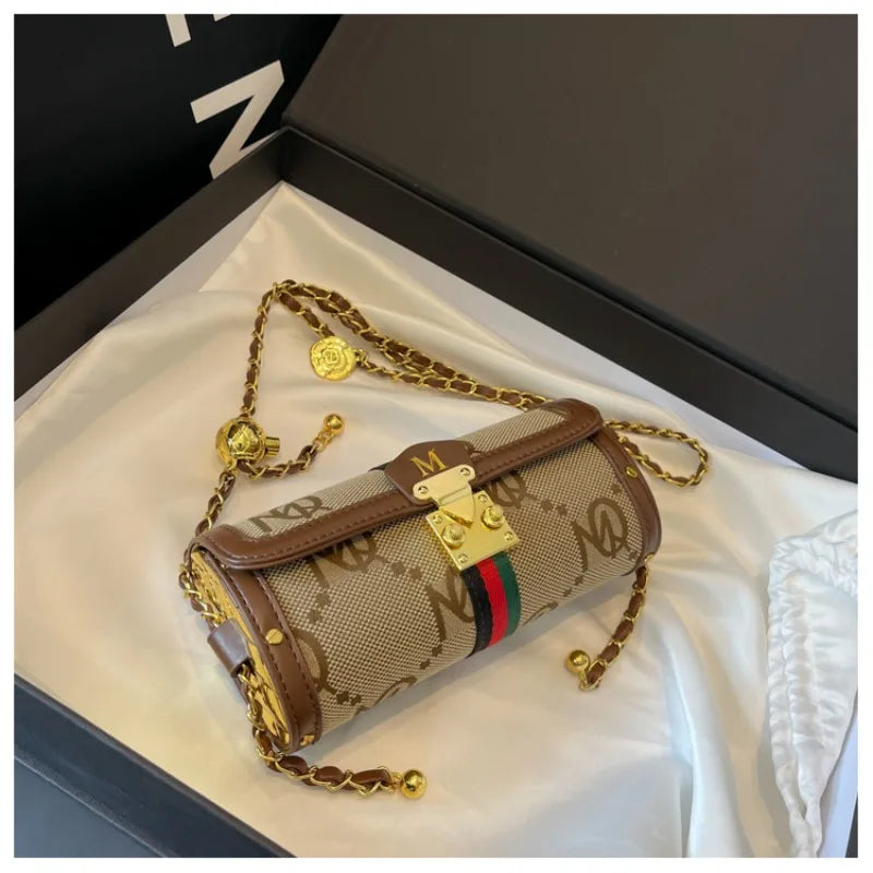 Designer handbag with gold chain and logo details on a white surface