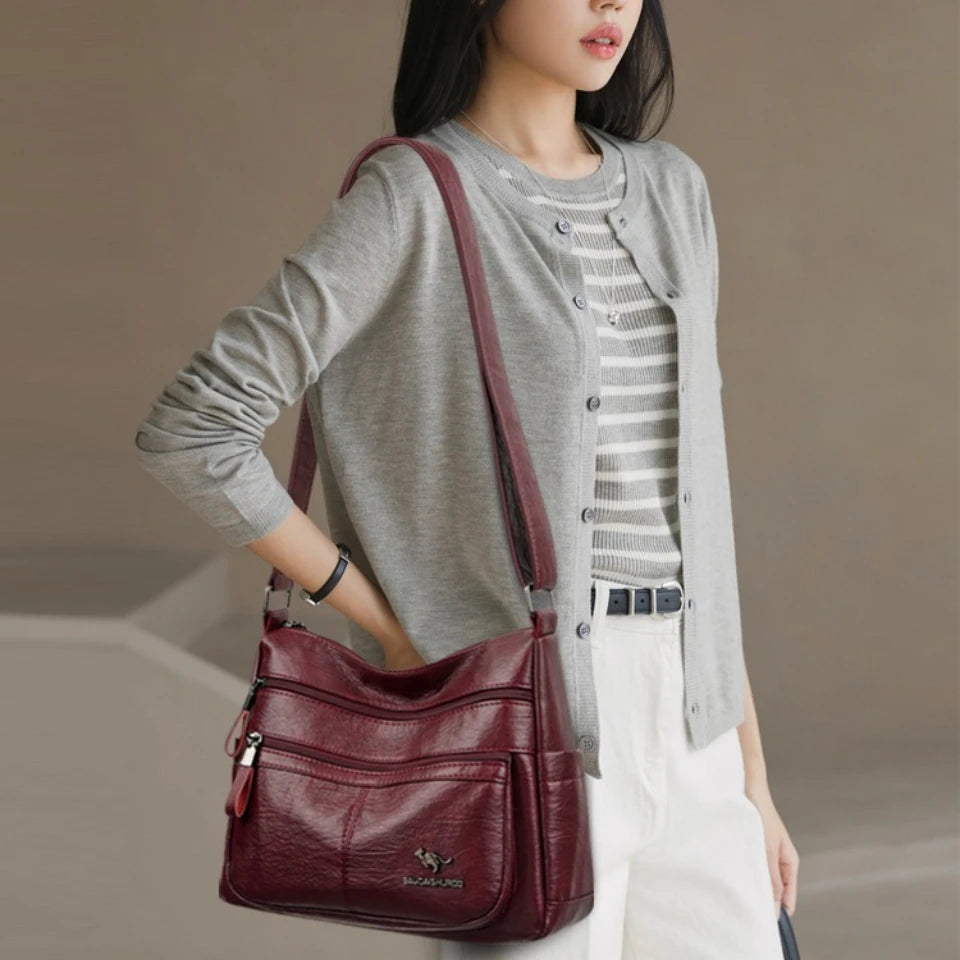 Woman carrying a maroon handbag against a neutral background