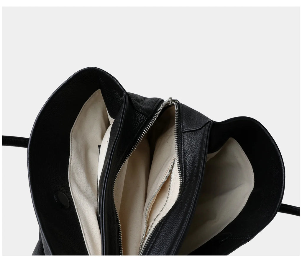 Black leather handbag with a zipper on a white background