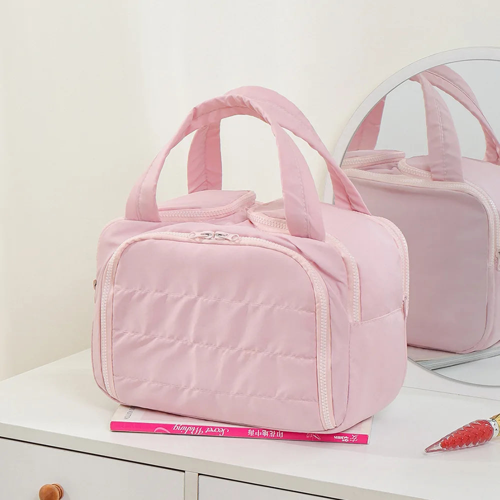 Pink travel bag on a white surface with a mirror in the background
