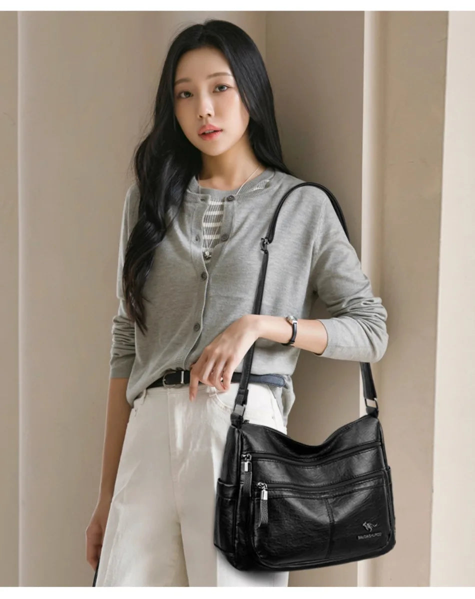 Woman holding a black handbag against a neutral background