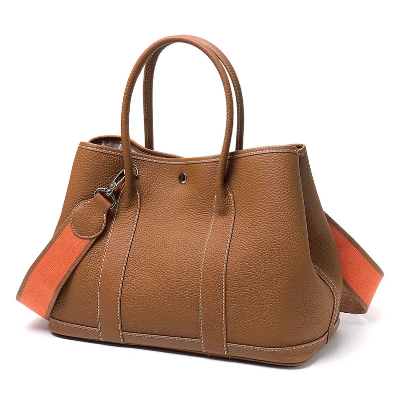 Brown leather handbag with an orange strap on a white background