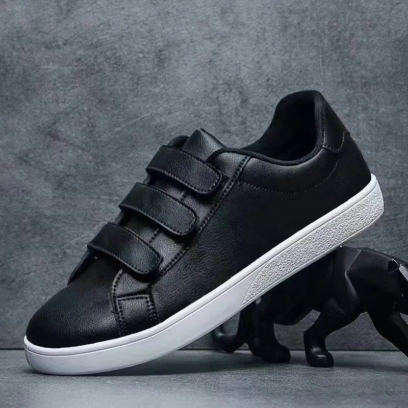 Black sneakers with velcro straps on a gray background