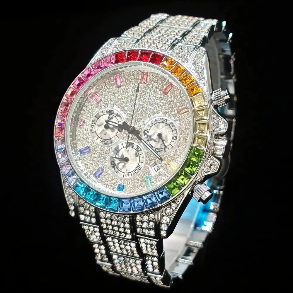 A silver-tone watch heavily embellished with clear rhinestones, featuring a rainbow-colored bezel with red, orange, yellow, green, blue, and pink stones, set against a solid black background.