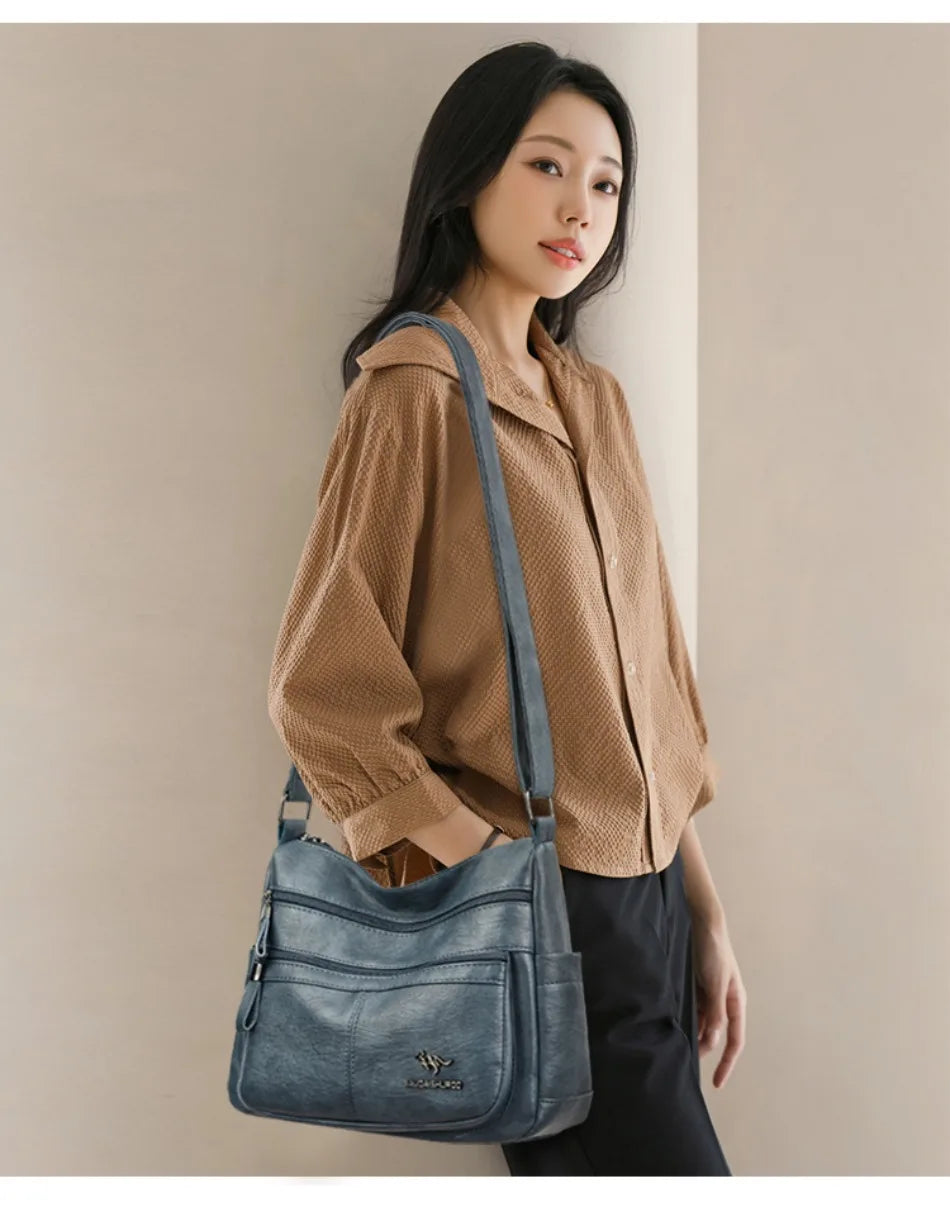 Woman carrying a blue handbag against a plain background