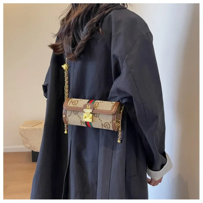 Person wearing a dark coat holding a patterned handbag with gold chain strap.
