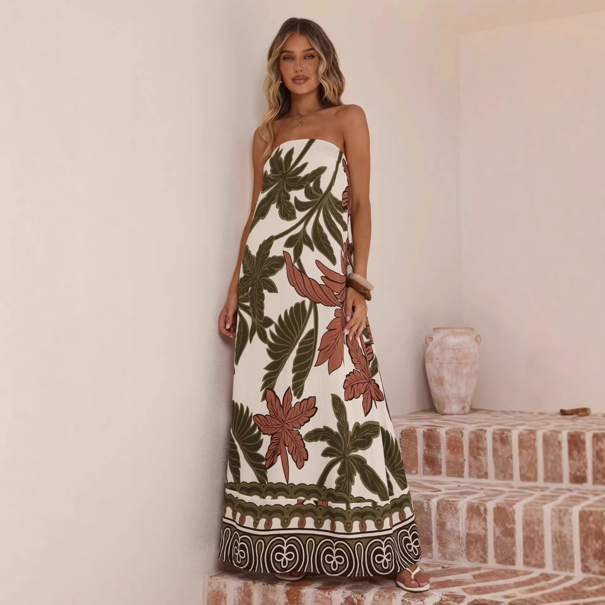 Woman wearing a strapless floral dress standing in front of a neutral wall.