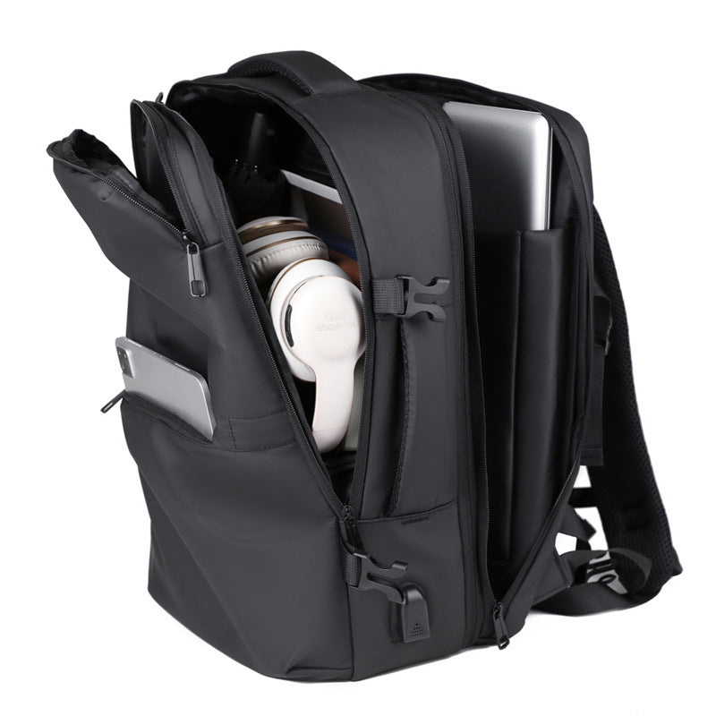 A black minimalist backpack with a top carry handle, side compression straps, and a front zippered pocket, shown against a clean white geometric background.