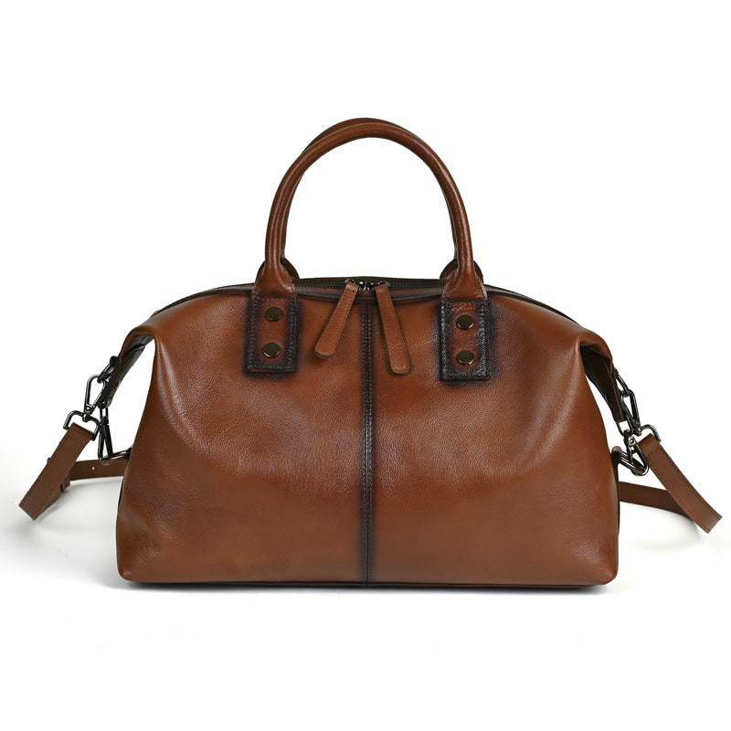 Brown leather handbag with black accents on a white background