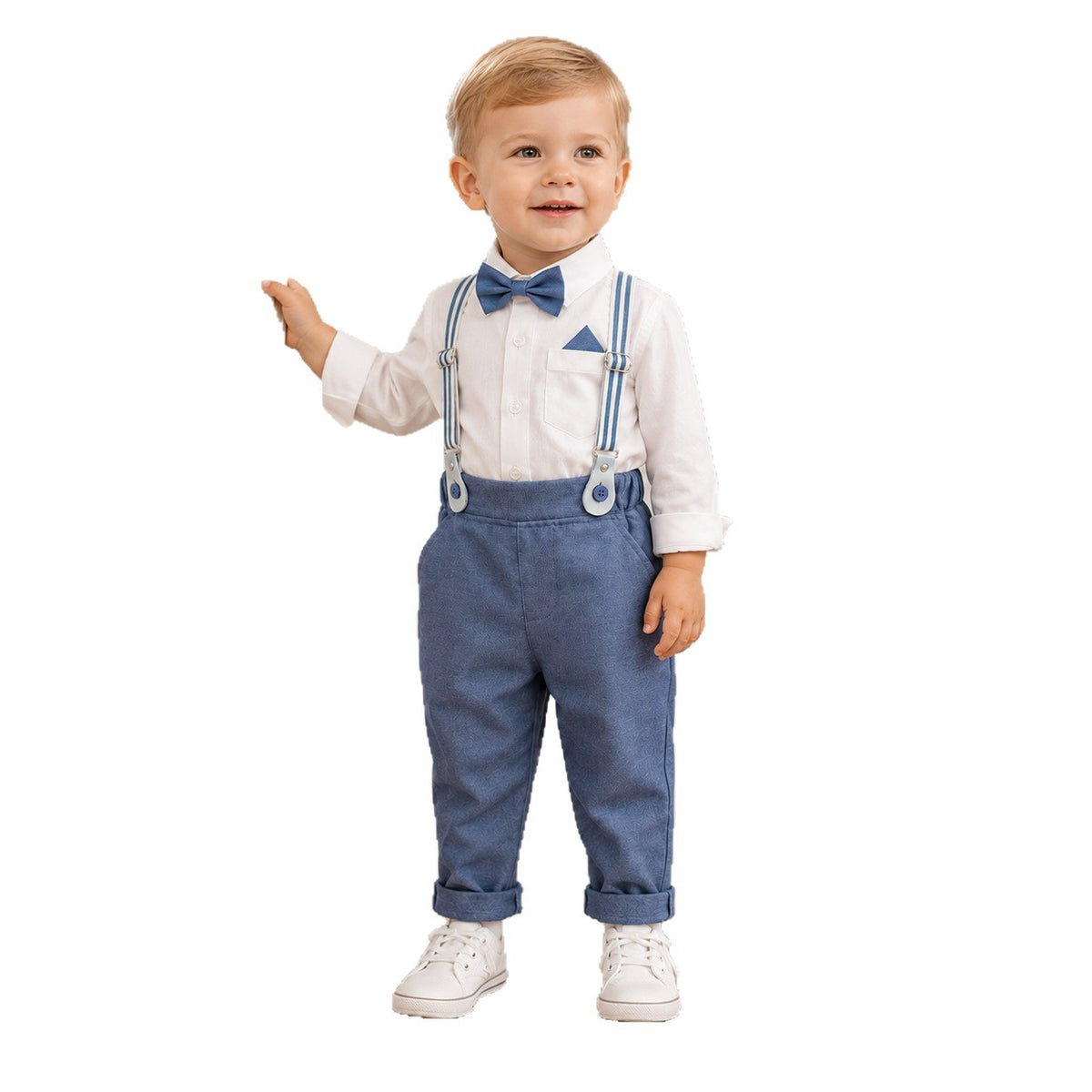 A toddler boy modeling a formal outfit consisting of a white long-sleeve shirt, blue suspenders, a blue bow tie, and a matching blue pocket square, paired with white sneakers, on a solid white background.