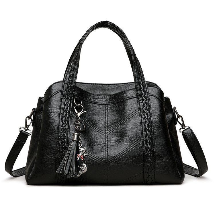 Black handbag with a decorative keychain on a white background